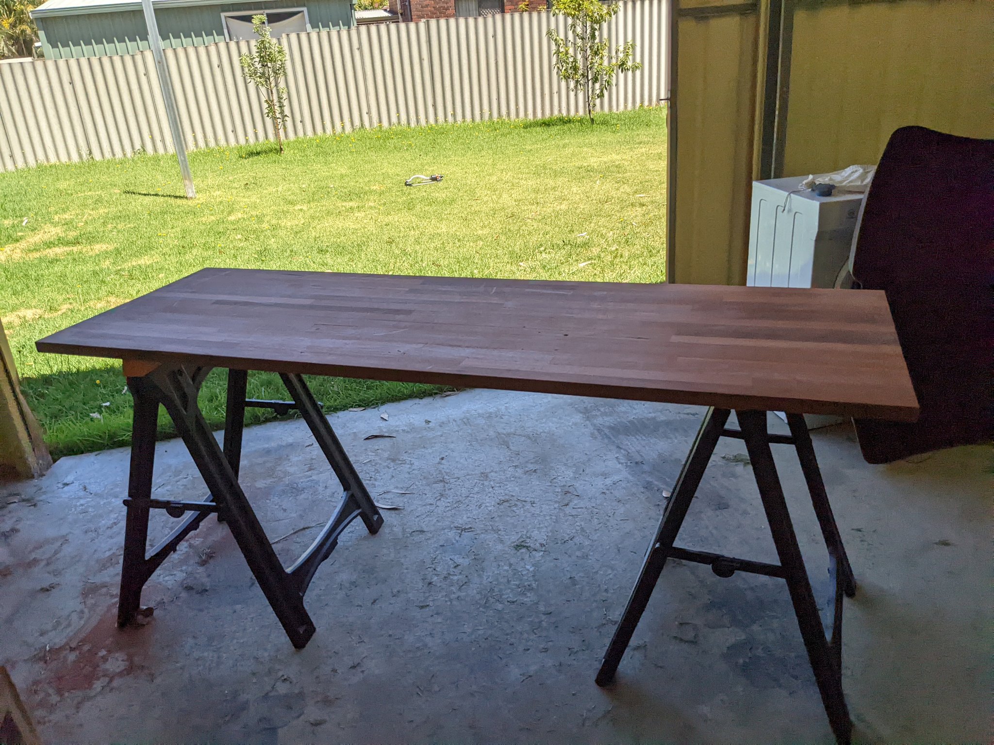 A Jarrah wooden desk top resting on saw horses